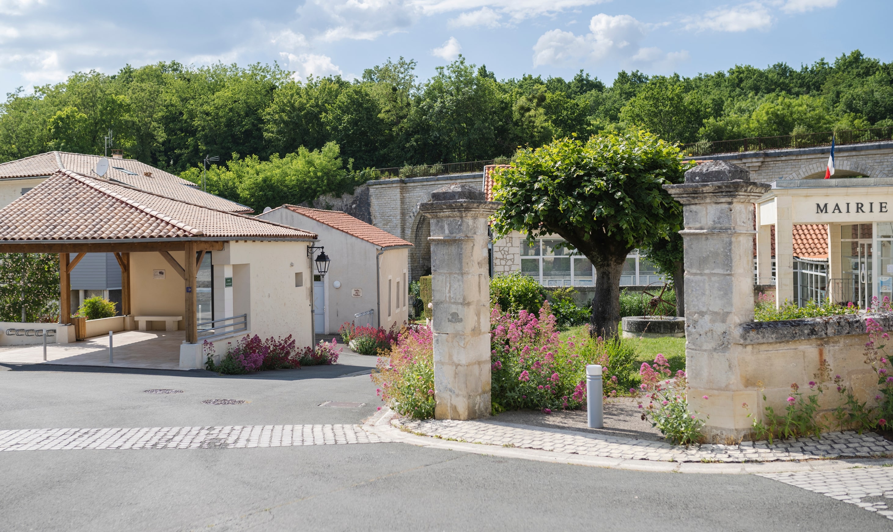 Centre-bourg aménagé avec mairie et halle pour les pèlerins, entourées d’espaces paysagers