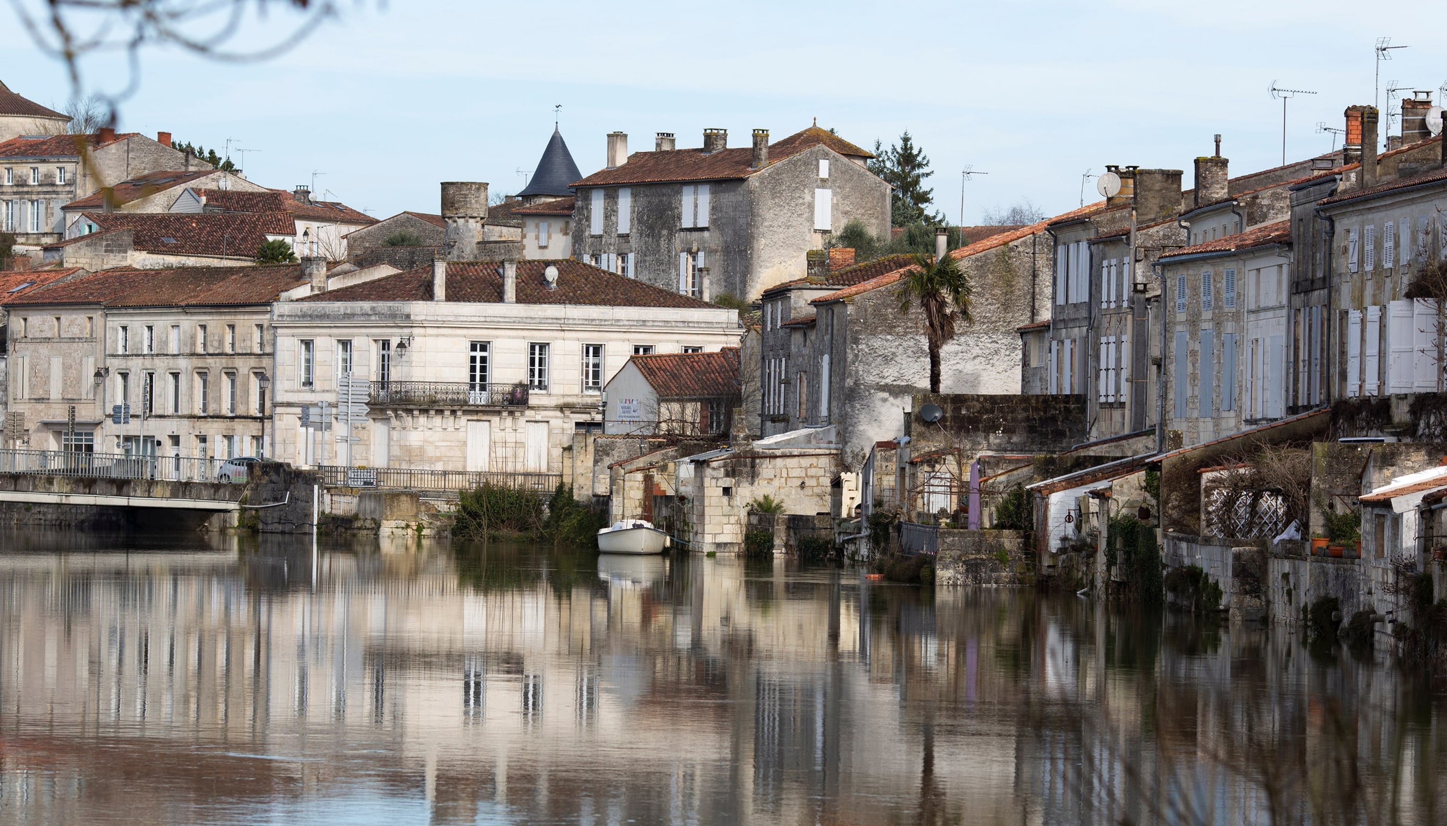 Centre ancien en bord de rivière, avec bâtiments en pierre et reflets sur l’eau.