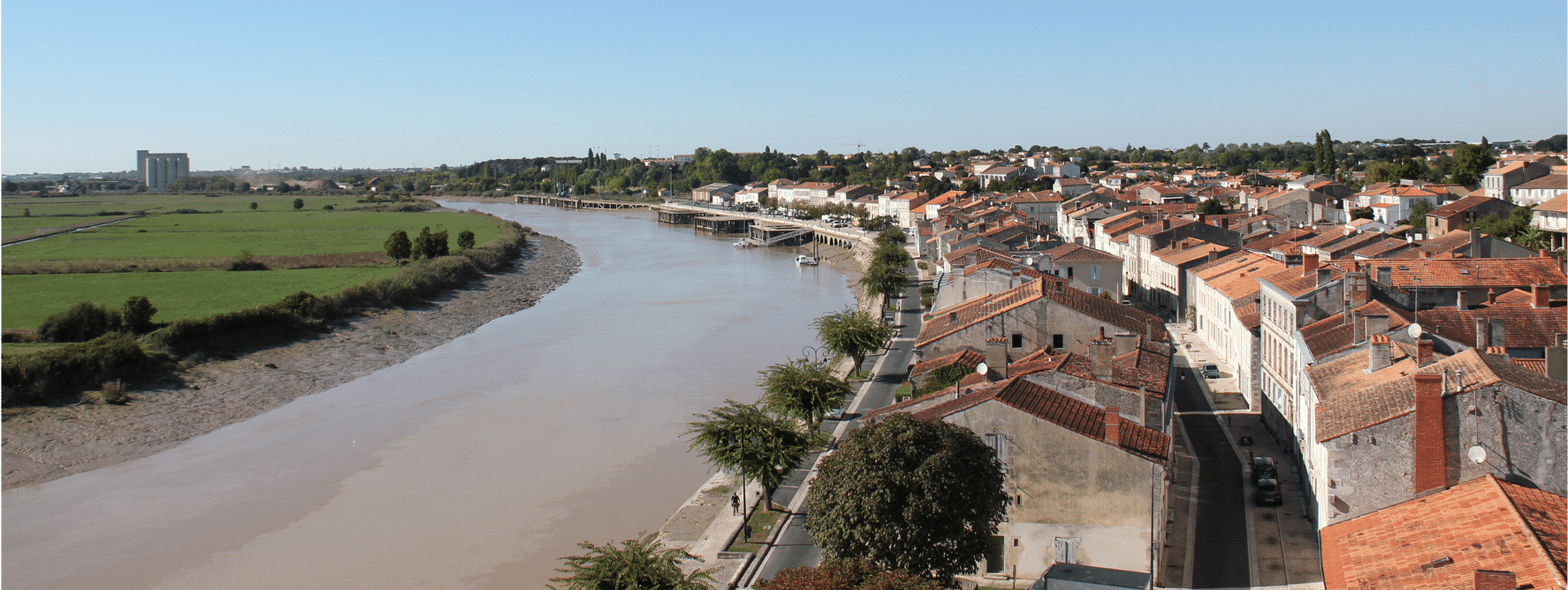 Centre-ville ancien en bord de rivière, avec habitat dense et paysage fluvial.